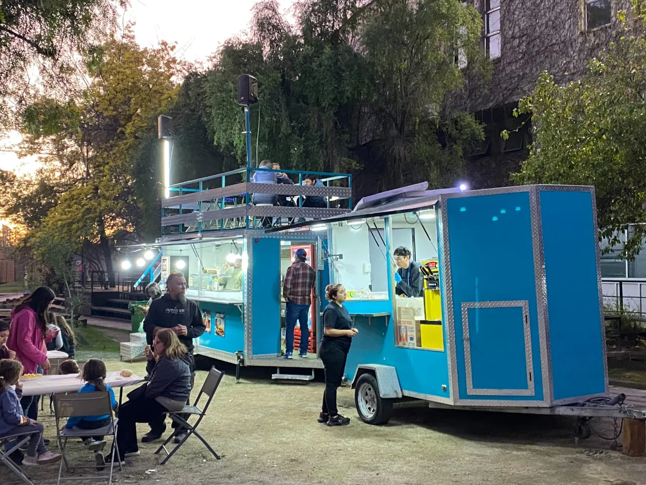 El carro iluminado de noche con clientes en las mesas
