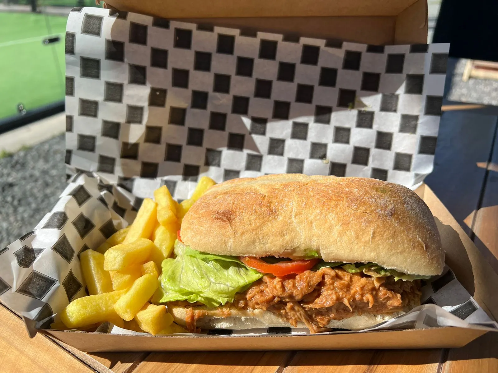 Sandwich de mechada en pan ciabatta con papas fritas en papel a cuadros
