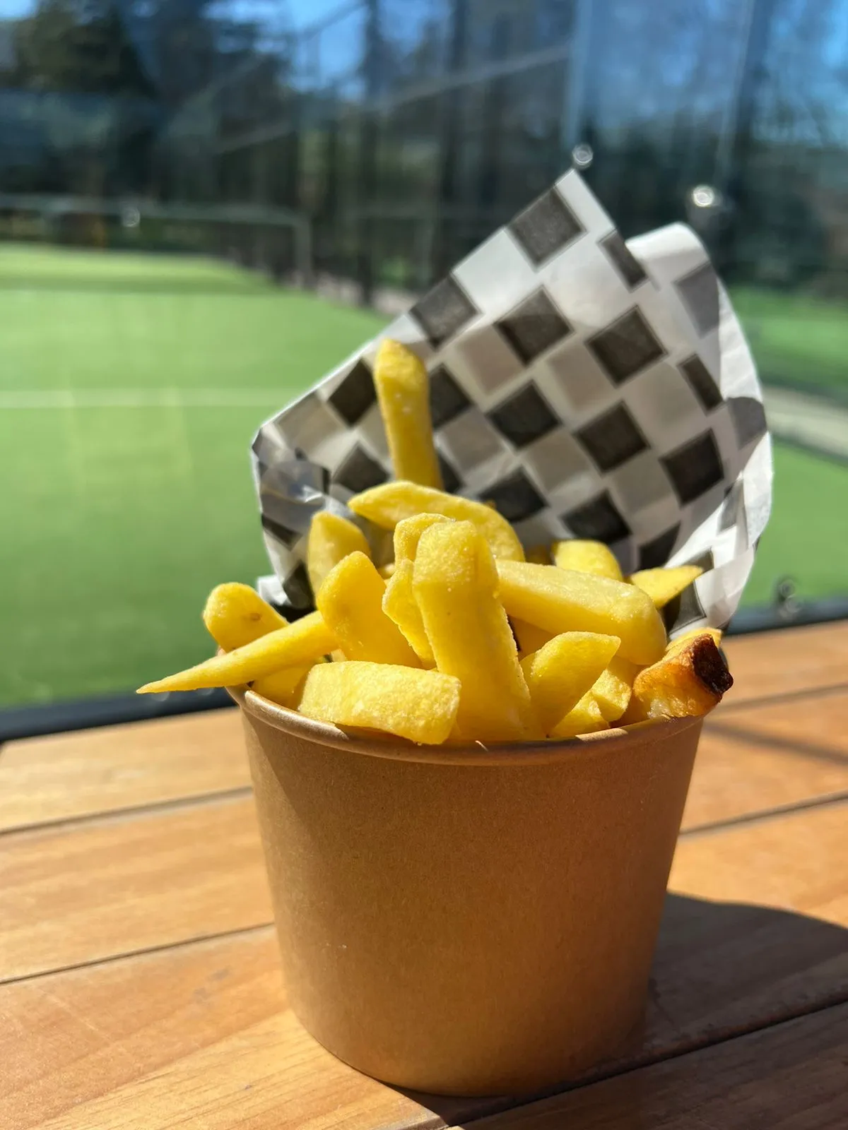 Papas fritas en cono de papel a cuadros con salsa